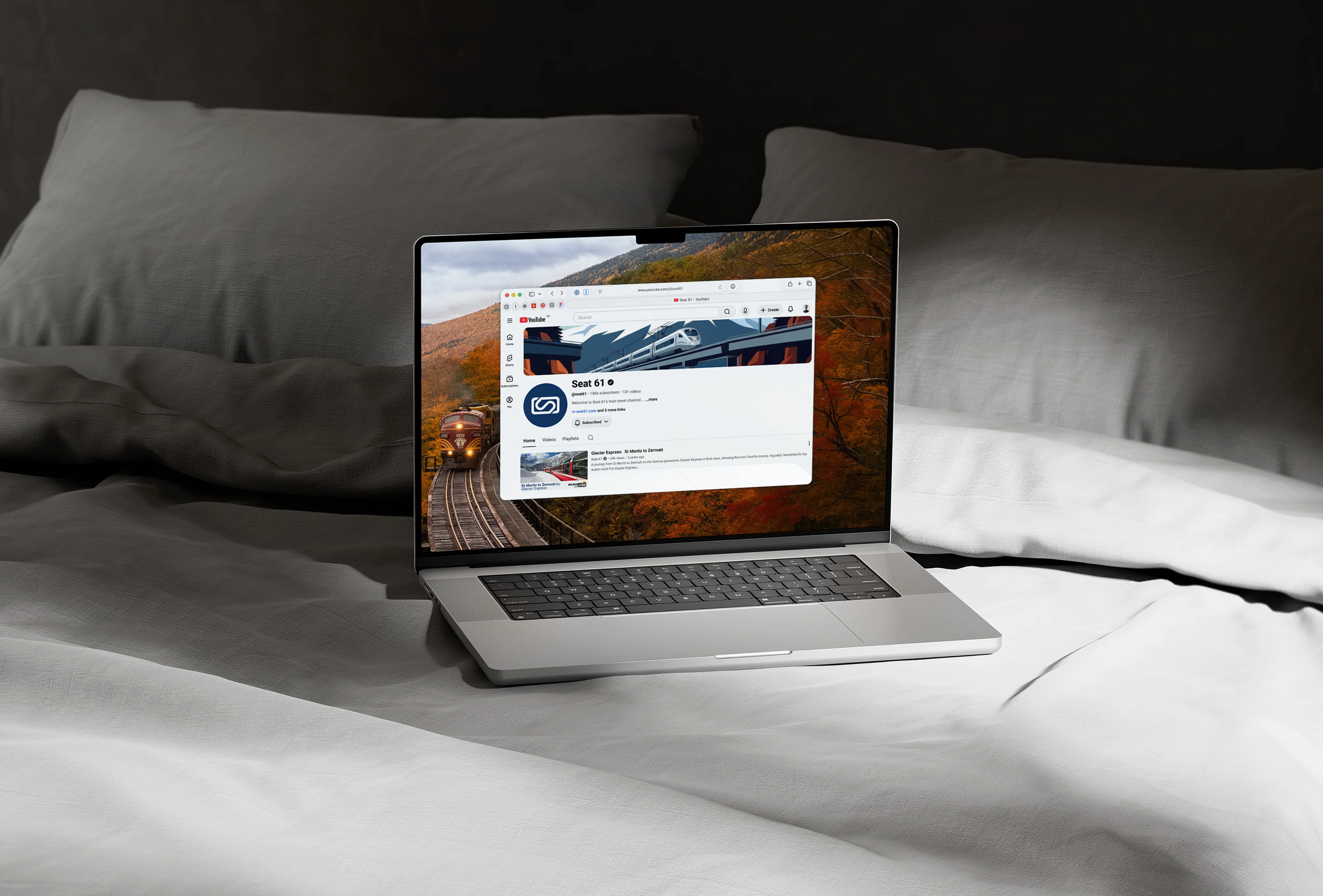 Lifestyle mockup of an open laptop on a bed, showcasing the banner and video layout of the Seat 61 YouTube page.